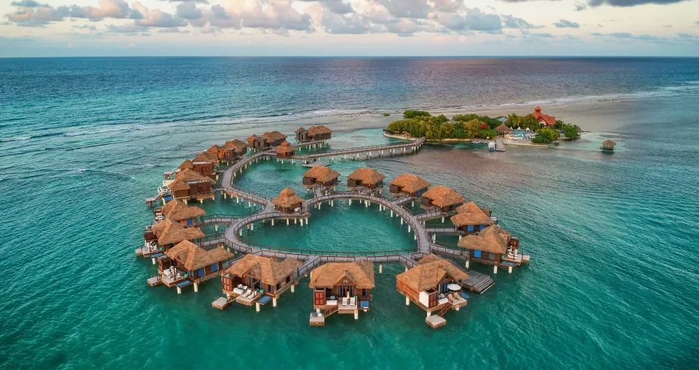 Aerial view of an overwater villa and turquoise beach